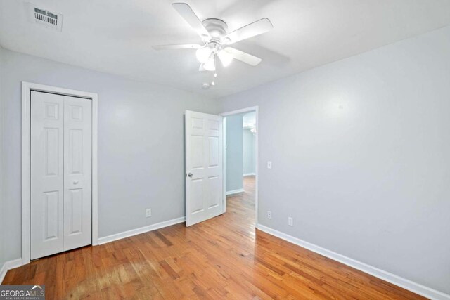 unfurnished bedroom with light hardwood / wood-style flooring, a closet, and ceiling fan