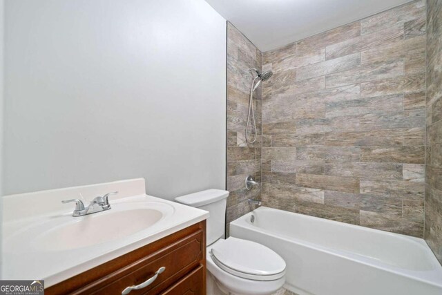 full bathroom with vanity, tiled shower / bath combo, and toilet