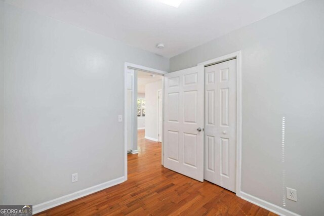 unfurnished bedroom with wood-type flooring and a closet