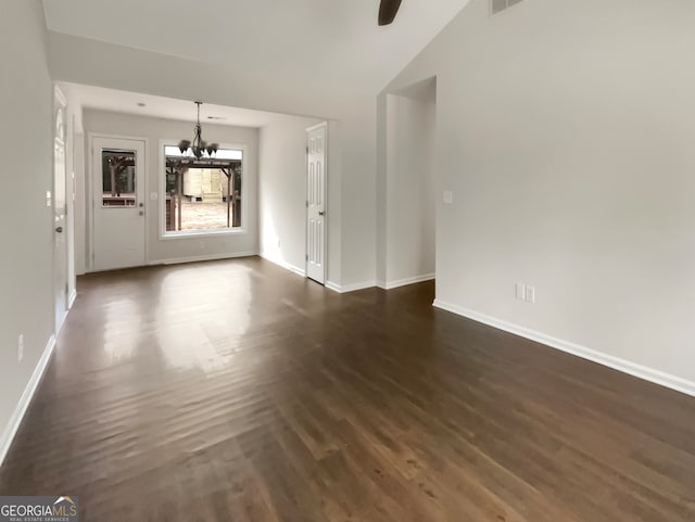 unfurnished living room with dark wood-type flooring, lofted ceiling, and a chandelier