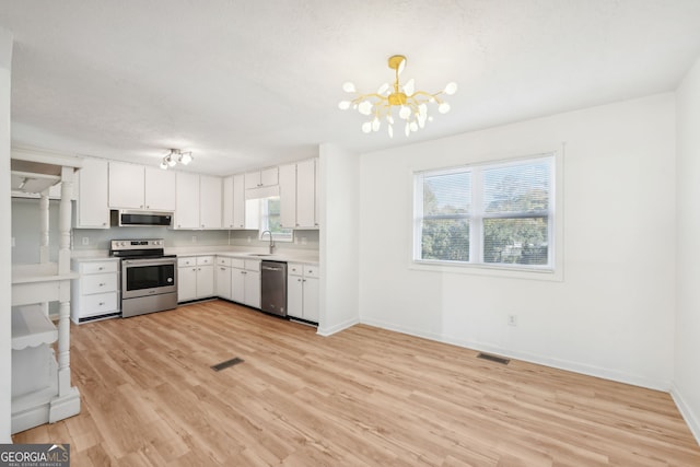 kitchen with stainless steel appliances, white cabinetry, a wealth of natural light, and sink