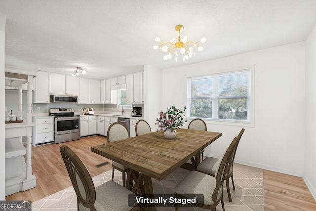 dining space featuring a chandelier, light wood-style flooring, and baseboards