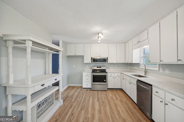 kitchen featuring white cabinetry, sink, stainless steel appliances, and light wood-type flooring