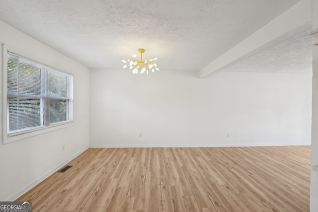 unfurnished room featuring a textured ceiling, light wood-type flooring, baseboards, and a notable chandelier