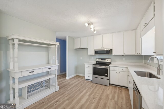 kitchen featuring white cabinets, sink, appliances with stainless steel finishes, and light hardwood / wood-style flooring