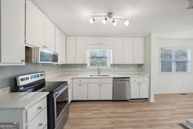 kitchen featuring light hardwood / wood-style floors, white cabinetry, sink, and appliances with stainless steel finishes