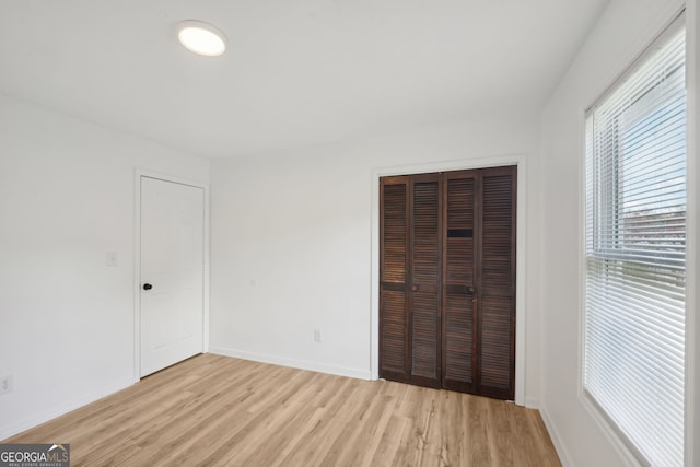 unfurnished bedroom with light wood-type flooring and a closet