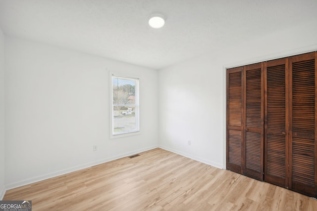 unfurnished bedroom with a closet, light wood-style flooring, and baseboards