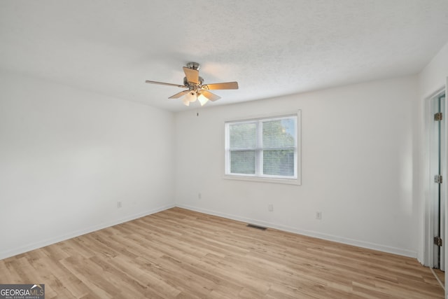 empty room featuring a textured ceiling and light hardwood / wood-style floors