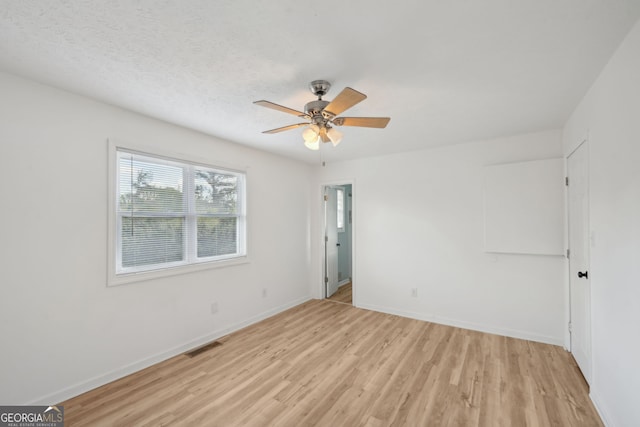 empty room featuring a textured ceiling, light hardwood / wood-style floors, and ceiling fan