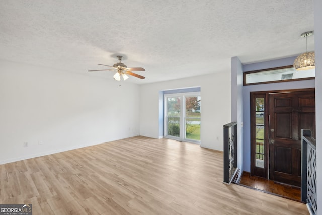 foyer entrance with ceiling fan, light hardwood / wood-style flooring, and a textured ceiling