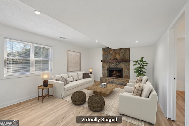 living room with a fireplace, light hardwood / wood-style flooring, and a textured ceiling