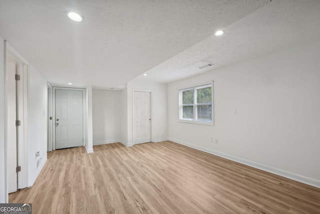 empty room with light hardwood / wood-style flooring and a textured ceiling