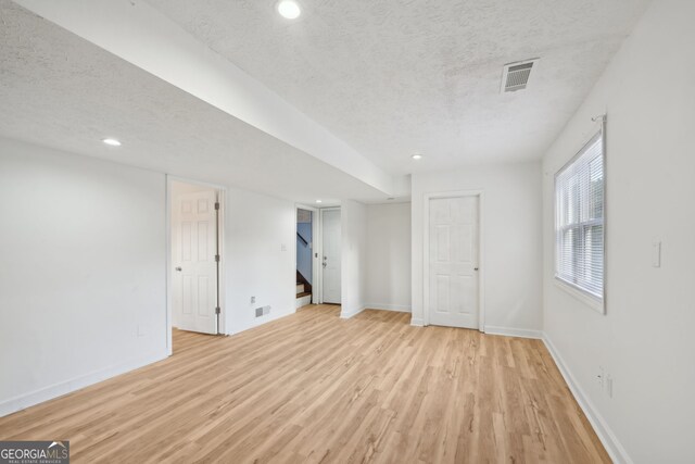 basement with light hardwood / wood-style flooring and a textured ceiling