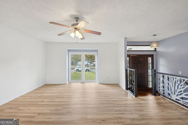 unfurnished room with a textured ceiling, light hardwood / wood-style flooring, and ceiling fan