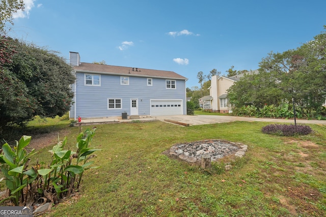 rear view of house with a garage, concrete driveway, a yard, and a chimney