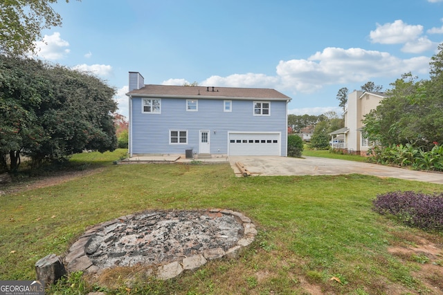 rear view of house with a yard, a garage, and an outdoor fire pit