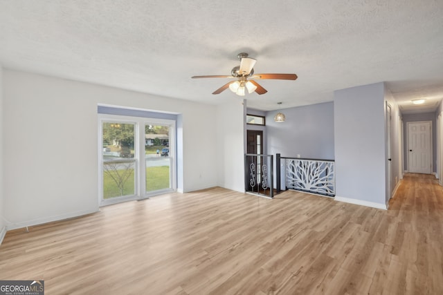 unfurnished room featuring a textured ceiling, light wood-type flooring, and ceiling fan