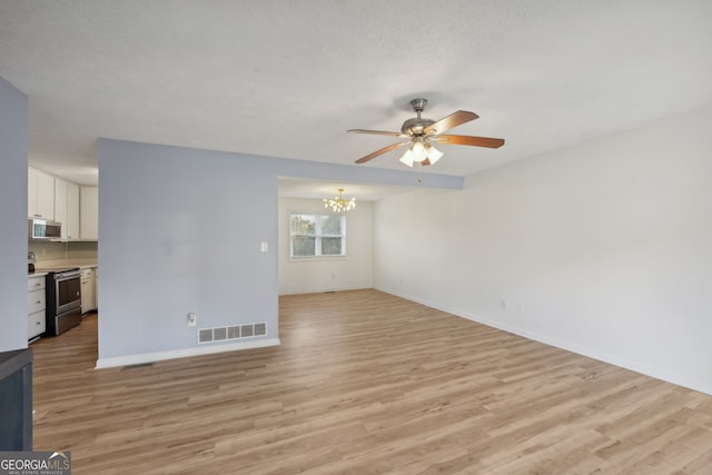 unfurnished living room with a textured ceiling, ceiling fan with notable chandelier, and light hardwood / wood-style floors