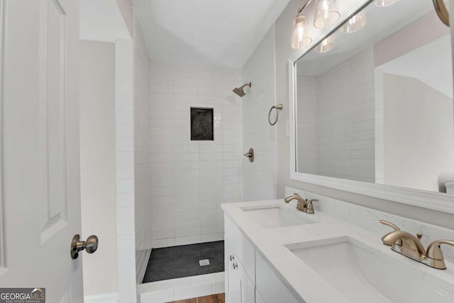 bathroom featuring vanity, a tile shower, and wood-type flooring