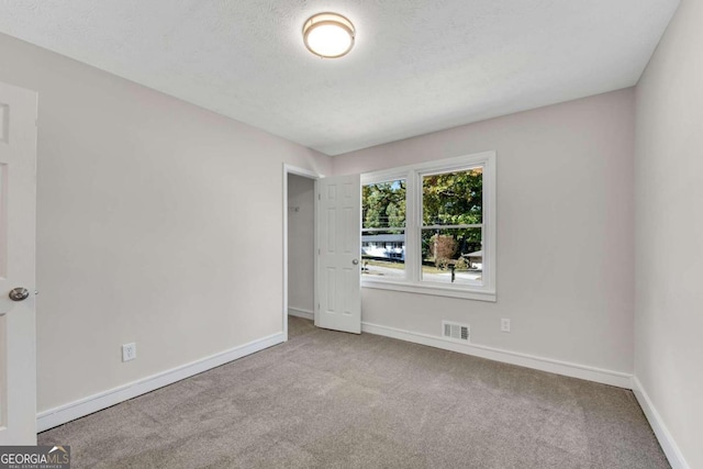 unfurnished room with a textured ceiling and light colored carpet