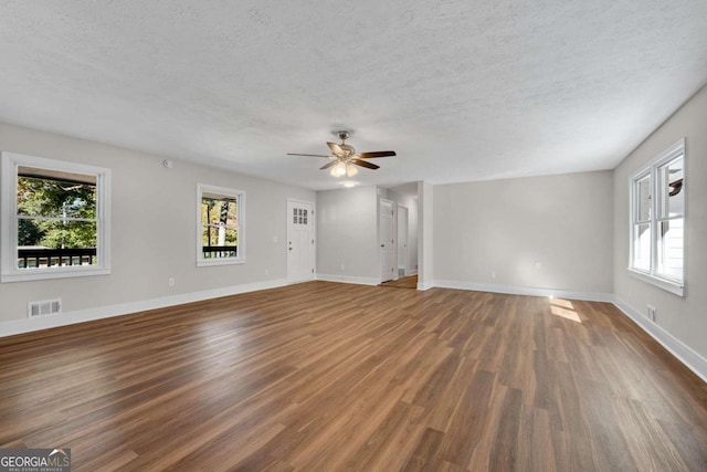 unfurnished living room with ceiling fan, a textured ceiling, and dark hardwood / wood-style floors