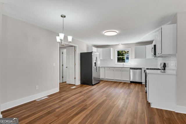 kitchen featuring appliances with stainless steel finishes, dark hardwood / wood-style flooring, white cabinetry, decorative light fixtures, and a notable chandelier