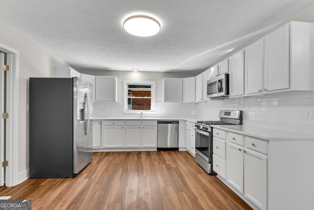 kitchen featuring decorative backsplash, light hardwood / wood-style flooring, white cabinetry, and stainless steel appliances