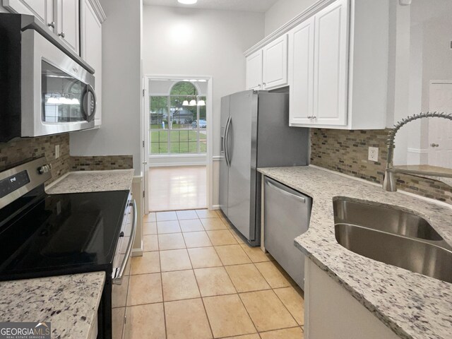 kitchen with decorative backsplash, white cabinetry, vaulted ceiling, sink, and stainless steel appliances