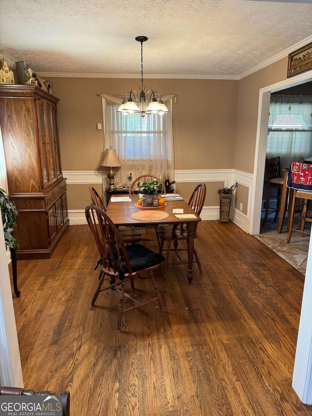 dining room featuring crown molding, a textured ceiling, dark hardwood / wood-style flooring, and an inviting chandelier