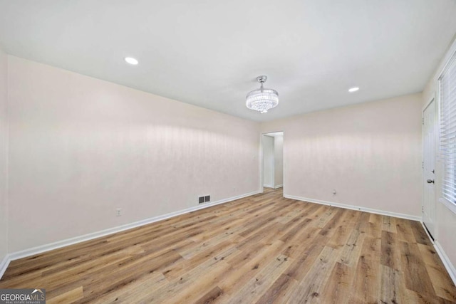 spare room featuring light hardwood / wood-style flooring and a notable chandelier