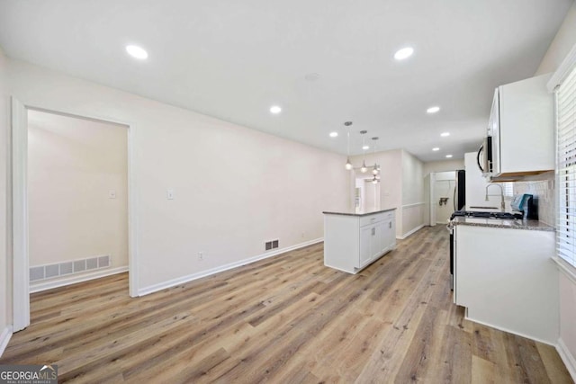 kitchen with light hardwood / wood-style floors, white cabinets, decorative light fixtures, and a kitchen island