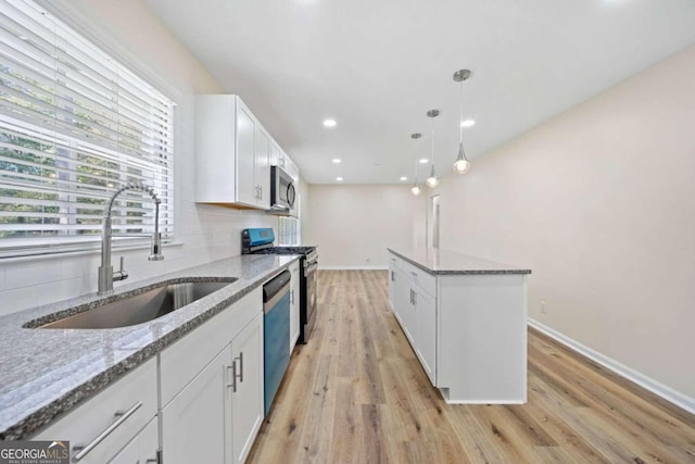 kitchen with light stone countertops, appliances with stainless steel finishes, sink, and white cabinets