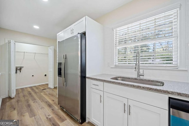 kitchen featuring light hardwood / wood-style flooring, stainless steel refrigerator with ice dispenser, sink, light stone countertops, and white cabinetry