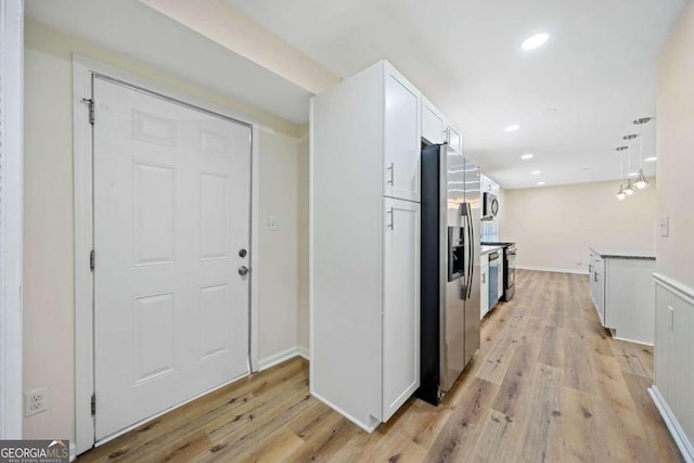 kitchen with appliances with stainless steel finishes, white cabinetry, and light hardwood / wood-style floors