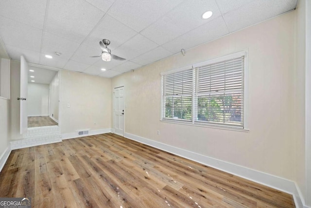 empty room with ceiling fan, wood-type flooring, and a drop ceiling