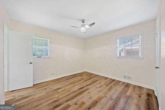 empty room with a wealth of natural light, light hardwood / wood-style floors, and ceiling fan