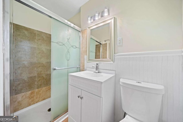 bathroom featuring vanity, a shower with shower door, and toilet