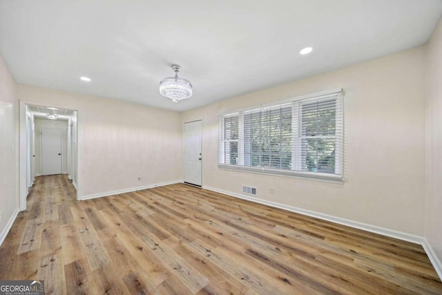 empty room featuring light hardwood / wood-style floors and an inviting chandelier