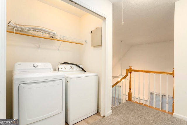 laundry area featuring a textured ceiling, light colored carpet, and washer and dryer