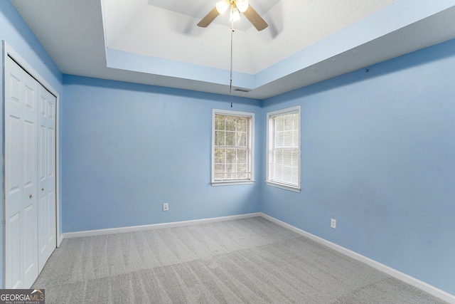 interior space featuring carpet flooring, ceiling fan, and a raised ceiling