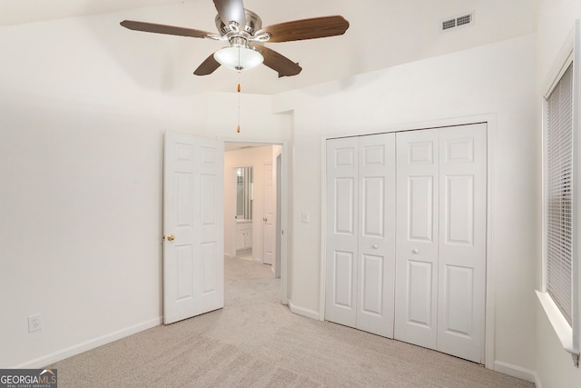 unfurnished bedroom featuring a closet, light colored carpet, and ceiling fan