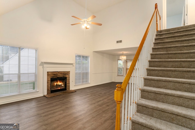 stairs featuring high vaulted ceiling, wood-type flooring, ceiling fan, and a fireplace