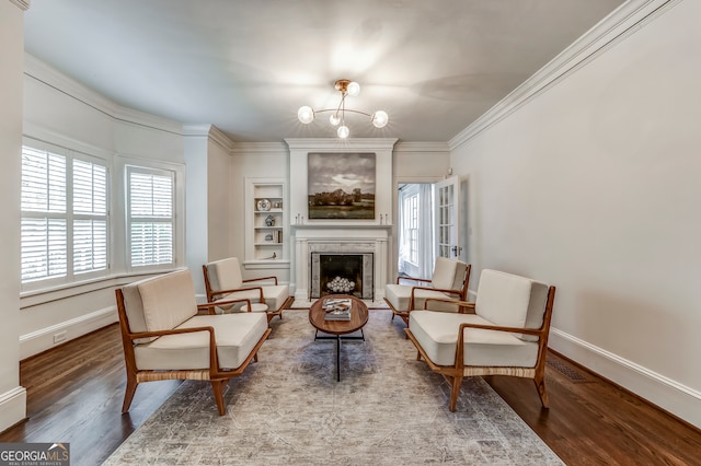 living area featuring crown molding, built in features, hardwood / wood-style flooring, and a chandelier