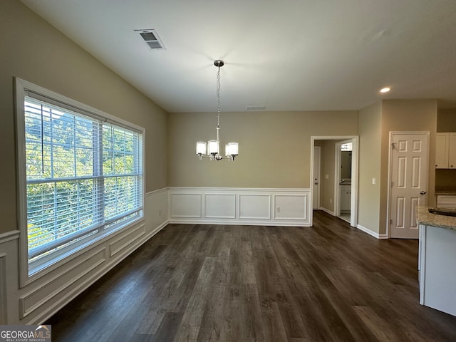 unfurnished dining area featuring dark hardwood / wood-style floors and a chandelier