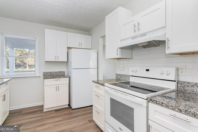 kitchen featuring hardwood / wood-style floors, white cabinets, dark stone counters, and white appliances