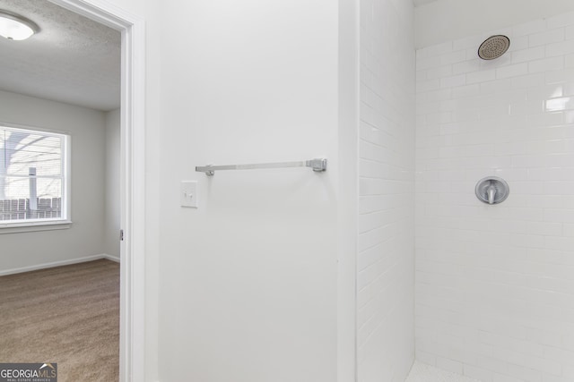 bathroom with tiled shower and a textured ceiling