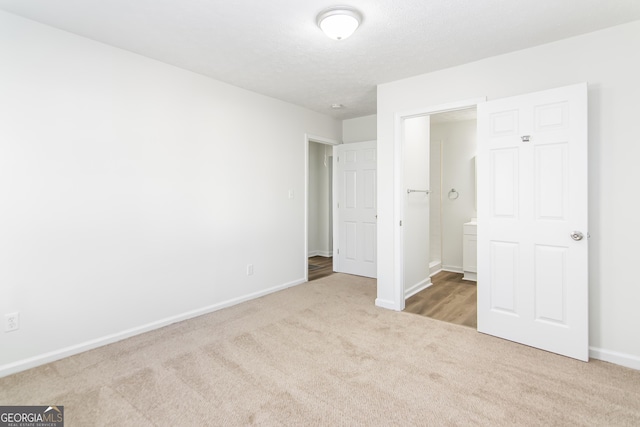 unfurnished bedroom with connected bathroom and light carpet