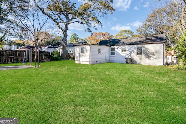 back of property with central air condition unit and a yard