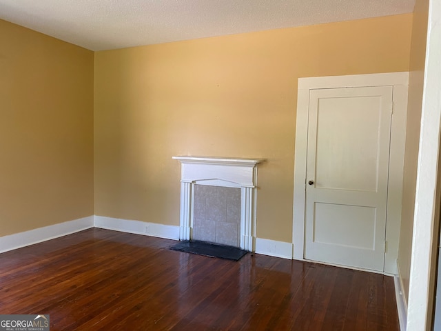 unfurnished living room with a textured ceiling and dark hardwood / wood-style flooring